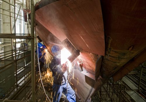 Welding new steel plates on a ship's hull during repair work on a ship in a dry dock.