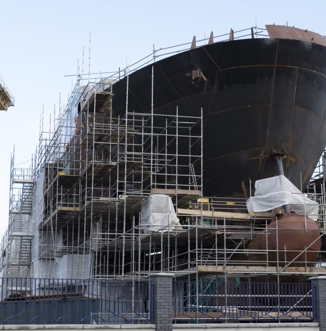 Shipbuilding progress scaffolding and crane large nautical vessel being built at dock port harbour harbour Glasgow traditional industry